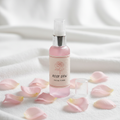 Rose water facial toner in pink spray bottle with rose petals
